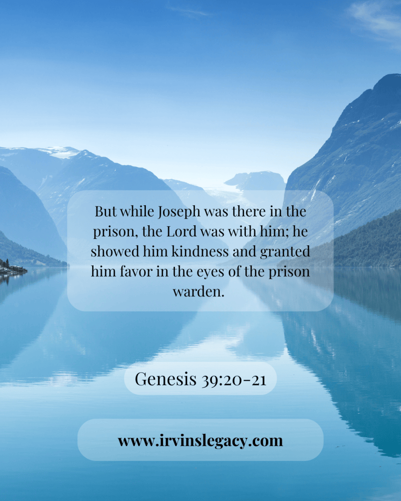 A serene landscape featuring a calm lake surrounded by mountains, with a biblical verse from Genesis 39:20-21 overlaid in a soft, translucent background.